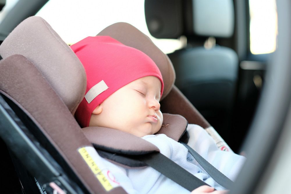Parent installing infant car seat in vehicle showing proper LATCH installation technique